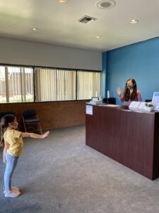 girl waving to person behind front desk at Irvine