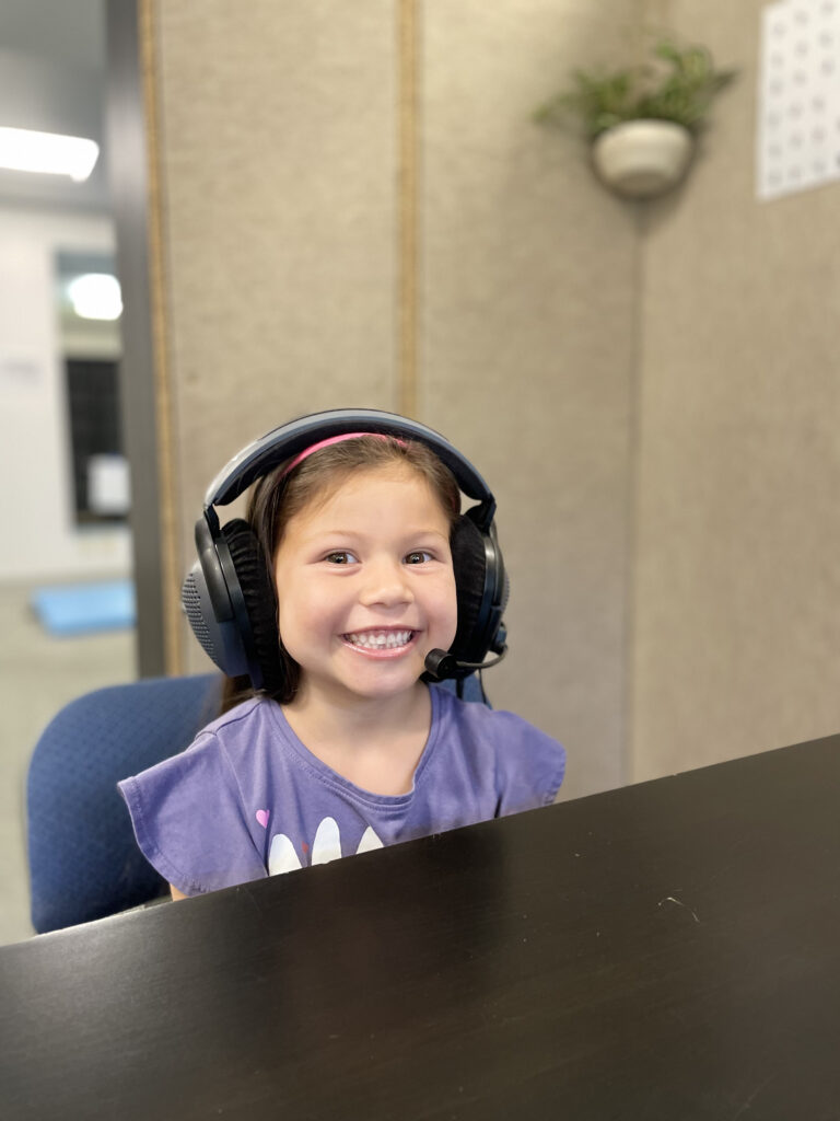 Stowell Learning Center student smiling and wearing headphones for a listening therapy session.