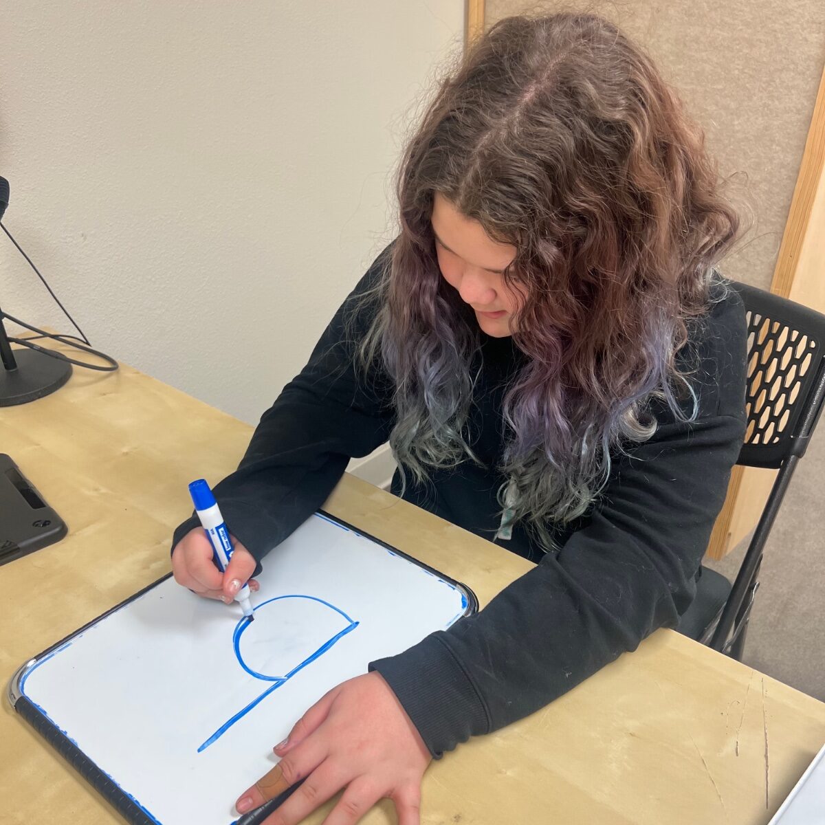 Student practicing letter formation by writing the letter b on a whiteboard during dyslexia therapy at Stowell Learning Center