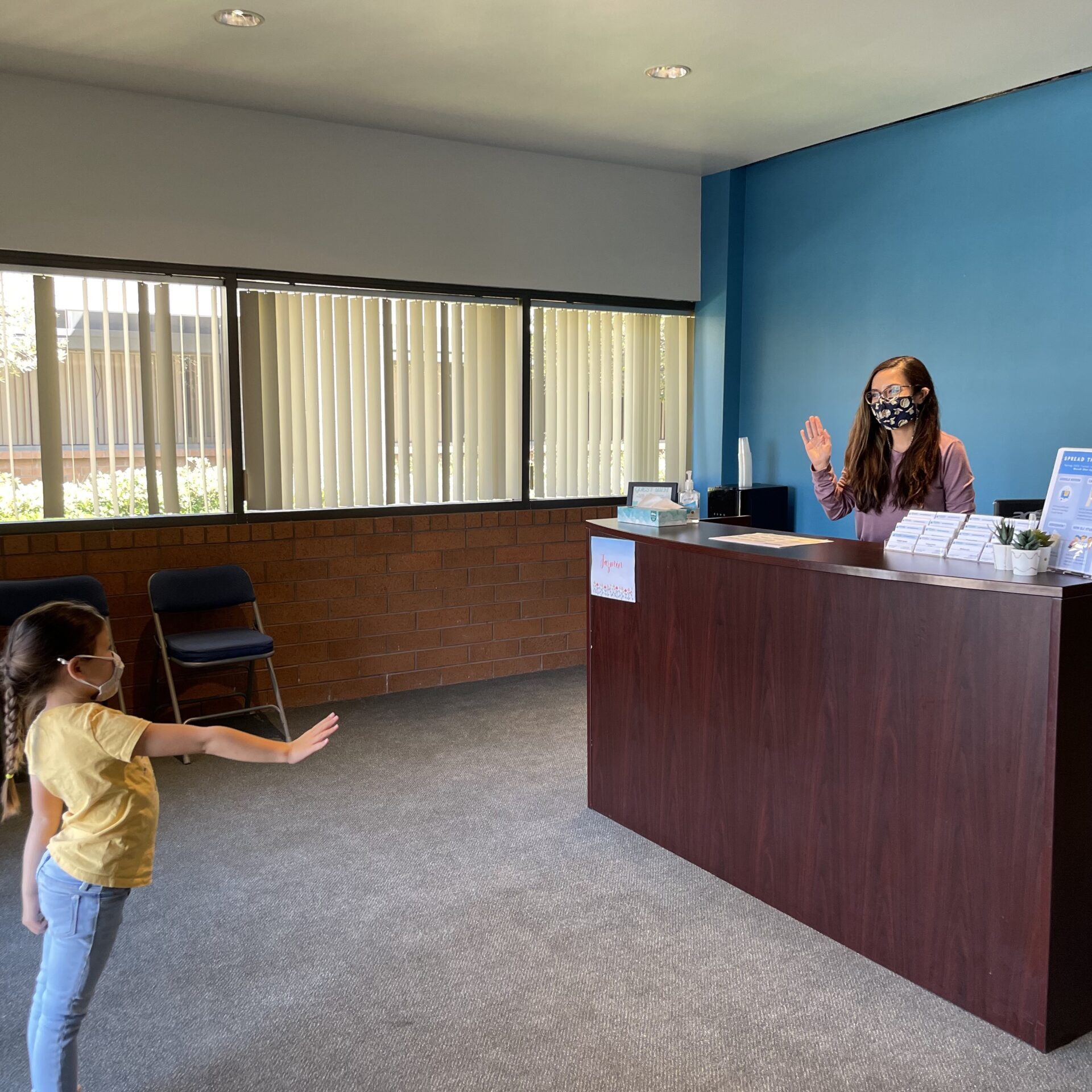 girl waving to person behind front desk at Irvine